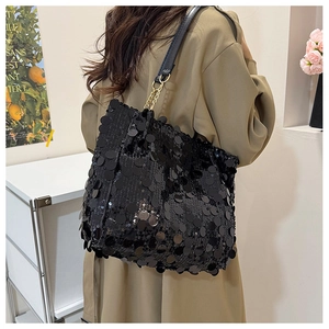 Détail d'un sac à paillettes noires avec de grandes paillettes et une chaîne en métal doré