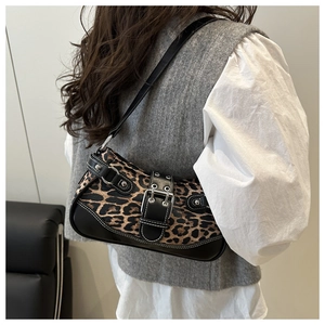 Detail of leopard print shoulder bag with black leather trim and buckle on a model
