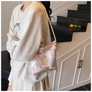 Detalle del patrón de mariposa bordada rosa y borla en un bolso tipo cubo de moda