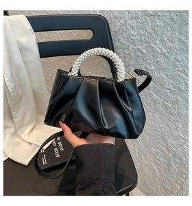 Detail of black pleated cloud bag with faux pearl handle and detachable crossbody strap