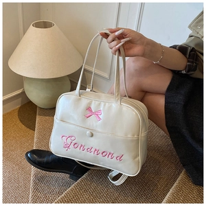 Detail view of cream-colored backpack featuring pink bow and elegant Gondnond embroidery