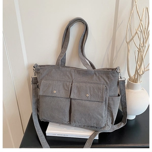Detail of grey corduroy tote bag featuring two front flap pockets and adjustable strap