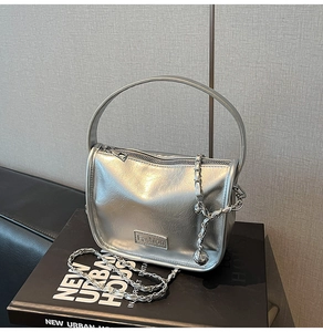 Détails de ce sac argenté en cuir verni avec logo métallique et chaîne de mode