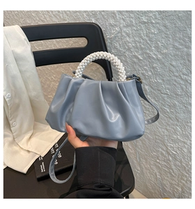 Detail of grey-blue pleated cloud bag showing pearl handle and fine PU leather texture