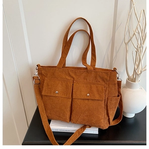 Detail of brown corduroy tote bag with dual front pockets and adjustable strap strap