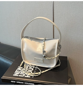 Détail du petit sac blanc crème en cuir verni avec chaîne dorée et pendentif boule