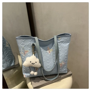 Dettaglio della borsa tote azzurra con texture a rilievo e ricami di farfalle colorate