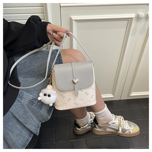 Close-up of mini bucket bag with cat pattern, heart lock, and plush ball detail
