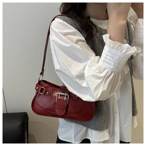 Detail of vintage dark red underarm bag with large silver buckle and smooth leather texture