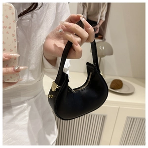 Detailed close-up of mini crescent moon bag with golden zipper and matte black leather