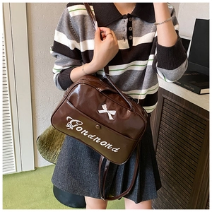Close-up of brown patent leather bag with white bow detail and Gondnond embroidery