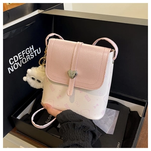 Detail of mini crossbody bag with heart lock and plush ball in a gift box packaging