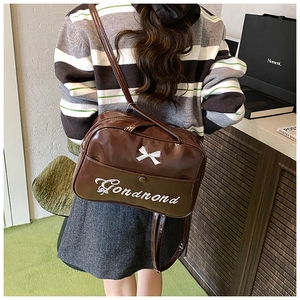Detail of coffee brown glossy backpack featuring white bow and embroidery embroidery