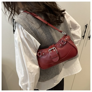 Detail of red faux leather shoulder bag featuring silver buckle and Y2K aesthetic style