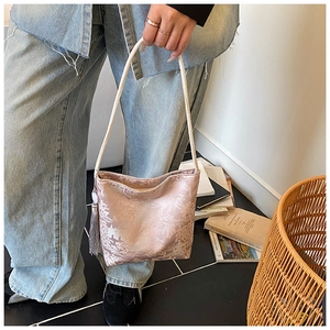 Detalle del bolso saco de jacquard rosa claro con borla elegante y textura floral de seda