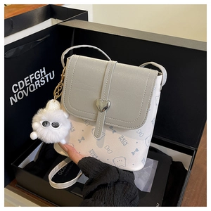 Detail of grey and white contrast shoulder bag with heart buckle and plush ball charm
