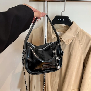 Sac bandoulière chic en cuir verni noir avec chaîne métallique et breloque boule