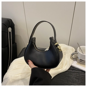 Detailed view of a black crescent handbag with gold hardware and smooth leather finish