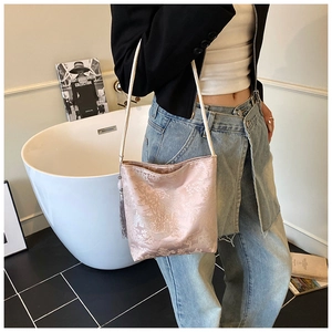 Detalle de bolso de hombro en brocado rosa con estampado floral y borla elegante