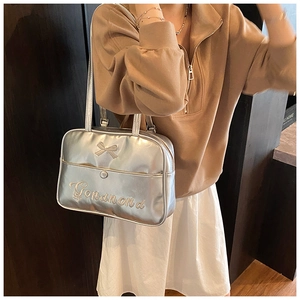 Detail of silver metallic bow backpack with embroidered branding and premium PU leather texture