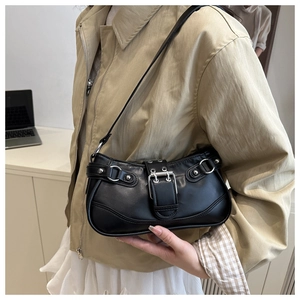 Detail view of black leather underarm bag featuring silver metal buckles and punk style studs