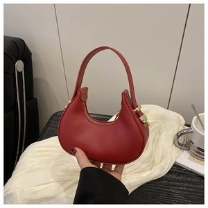 Detail of red crescent handbag with smooth leather finish and golden zipper hardware