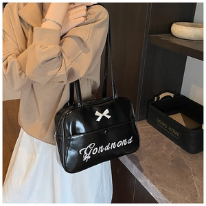 Detail of black glossy tote bag featuring white Gonandnd embroidery and a 3D bow accent