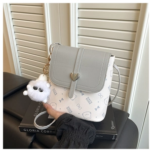 Detail of grey and white bucket bag with heart metal clasp and fluffy ball charm