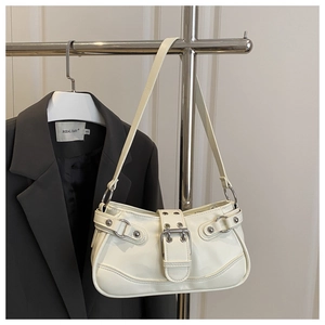 Detailed view of cream PU shoulder bag with silver rings and metal rivets on a hanger