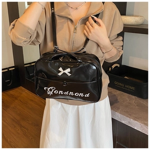 Detailed view of black glossy leather bag featuring white bow and elegant script lettering