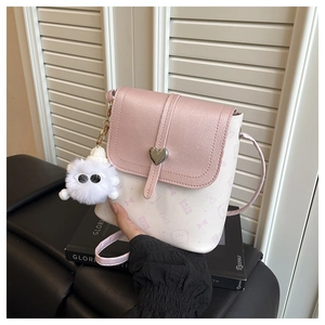 Close-up of mini pink and white crossbody bag with heart buckle and cute monster charm