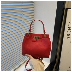 Detail of red lychee textured leather handbag featuring a gold square twist lock closure