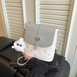 Mini bucket shoulder bag with grey contrast lid and plush charm on a book