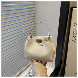 Detailed view of white litchi pattern leather bag with metallic twist lock and handle