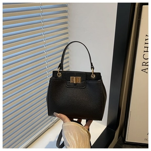 Close-up of black lychee grain leather handbag with gold twist lock and fine stitching
