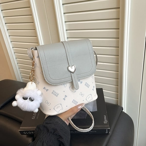 Mini cream bucket bag with cat pattern and heart metal buckle shown on a shelf