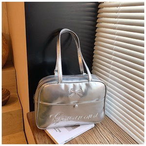 Detail of silver metallic leather handbag featuring a bow applique and embroidery on top