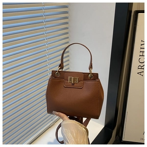 Close-up of caramel brown lychee leather handbag with a rectangular gold twist lock