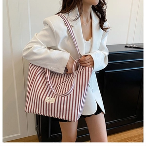 Detail of red and white striped canvas tote bag with adjustable shoulder strap and logo