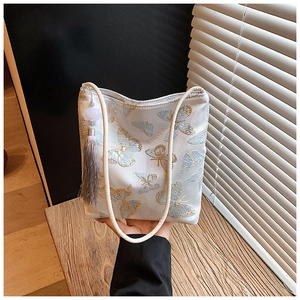 Detalle del bordado de mariposa y borla gris en un bolso tipo cubo de estilo chino