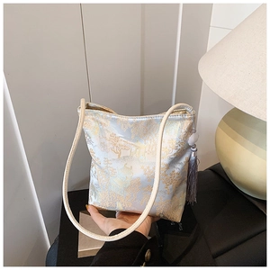 Primer plano de bolso tipo cubo de brocado azul con patrones dorados y elegante borla gris