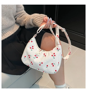 Dettaglio della borsa sottobraccio in velluto bianco con stampa ciliegia su una modella