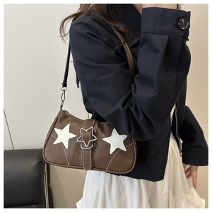 Detail of a brown leather Y2K shoulder bag with white star patches and metal star buckle
