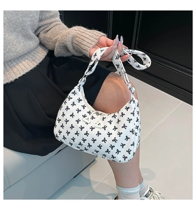 Detail of white hobo bag featuring black bow print and textured corduroy fabric finish