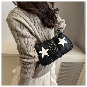 Close-up of a black denim shoulder bag with white star appliques and a silver star buckle
