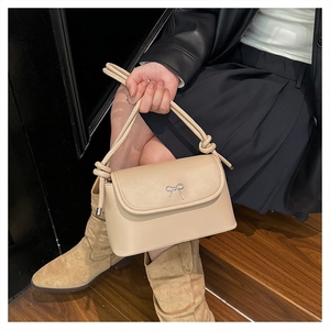 Detail of beige crossbody bag with silver metal bow and unique thick knotted handle