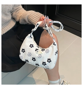 Detail of white corduroy underarm bag featuring black floral print and wide strap