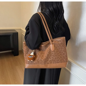 Detail view of leopard print tote bag with brown leather strap and monster charm