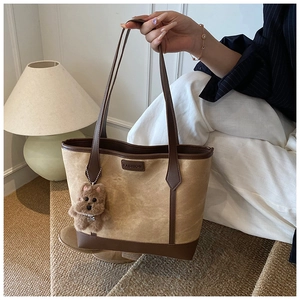Detail view of khaki tote bag with fashion logo and a cute brown puppy plush charm