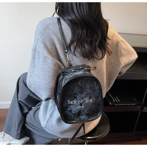 Close-up of a vintage black backpack with white letter print and silver hardware